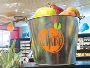 Metal bucket with Fresh Divide logo which is filled with fresh fruit